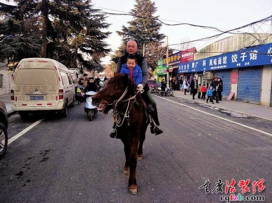 父子俩骑马走过街道本报记者李小刚摄